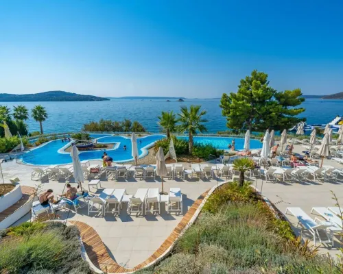 Piscine et chaises longues avec vue sur la mer au camping Roan Amadria Park Trogir.